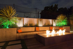 Outdoor fireplace lit up with outdoor lighting. Entertainment spaces